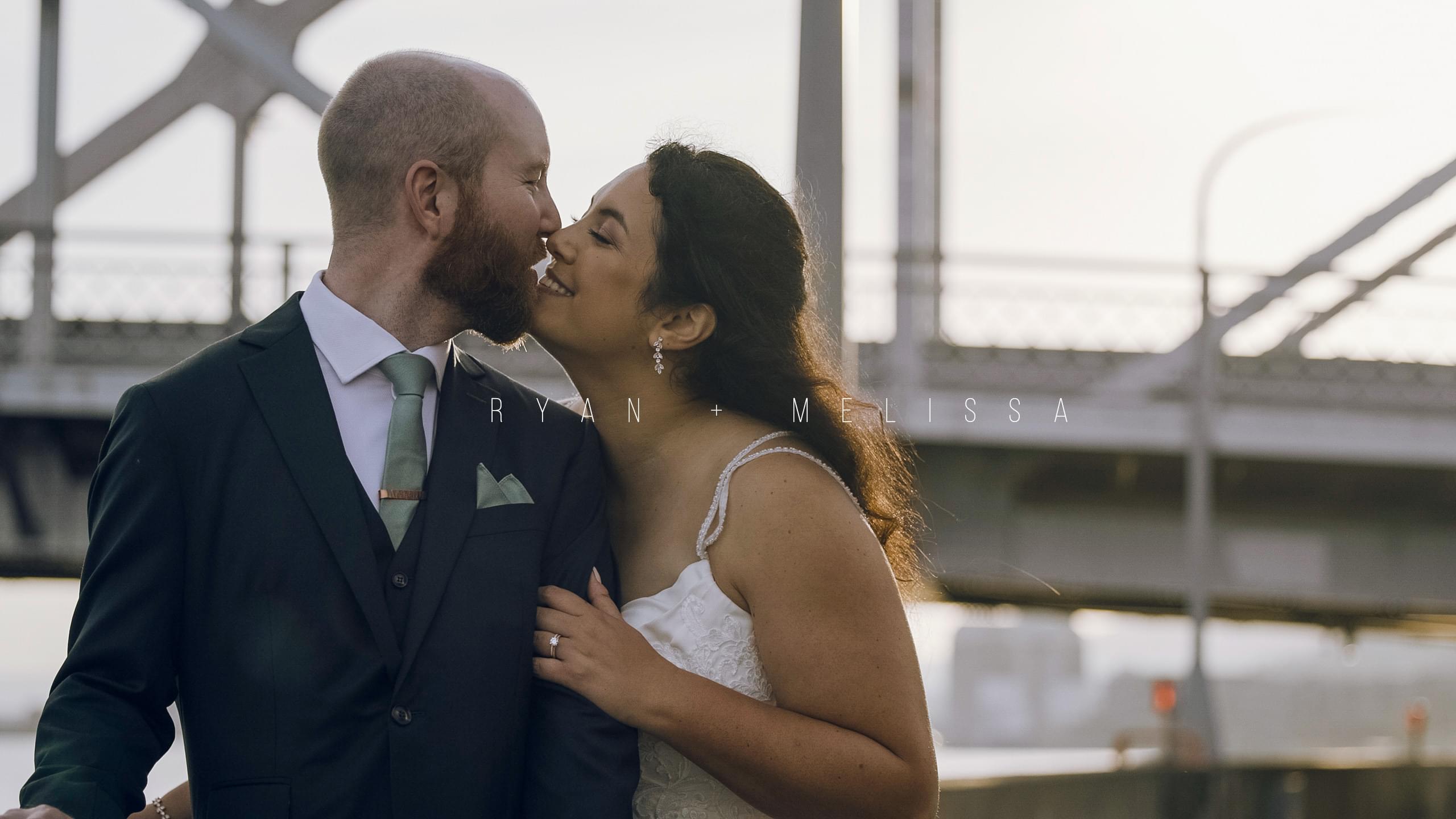 Melissa and Ryan sharing a romantic kiss in front of the Duluth lift bridge on their fall wedding day hero